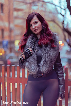 Jeny poses on a city street wearing just a stylish jacket, black seamless pantyhose and tall boots, her feminine curves and private areas fully on display